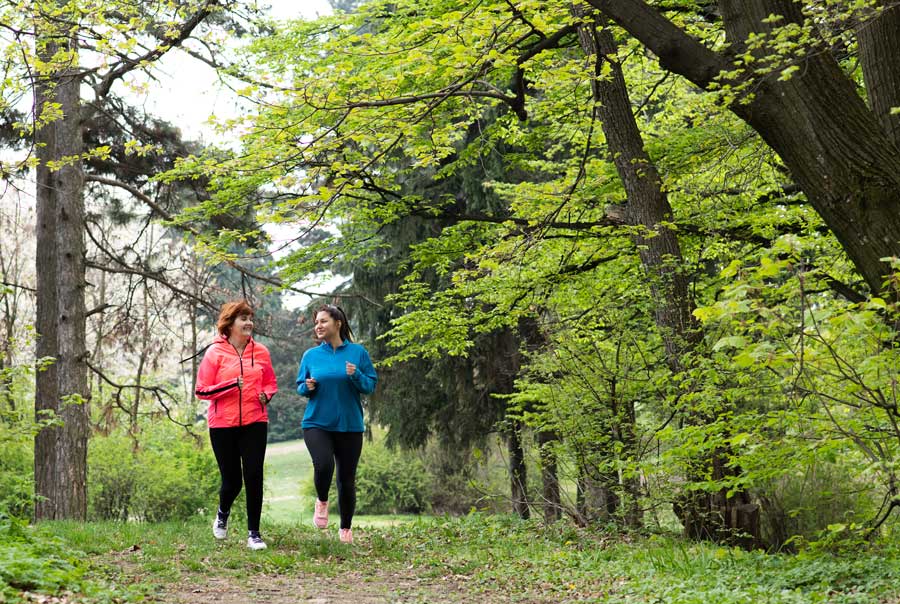Mother and daughter running in the woods.